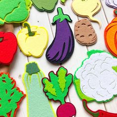 several cut out vegetables are displayed on a white table with wooden boards and paper cuttings