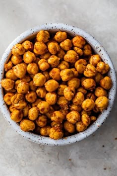 a white bowl filled with roasted chickpeas on top of a marble countertop