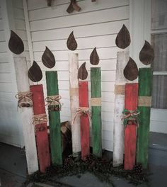 three wooden poles with christmas decorations on them in front of a white house and door