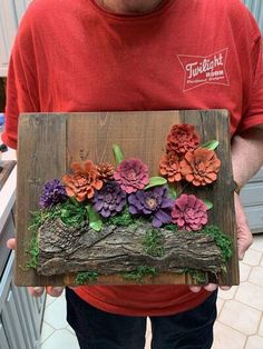 a man holding a piece of wood with flowers on it