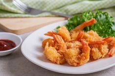 a white plate topped with fried shrimp next to a bowl of ketchup