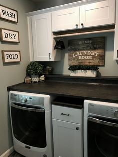 a washer and dryer are sitting in the corner of a laundry room with white cabinets