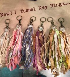 several different colored ribbons hanging from hooks on a wall with the words, new tassel key rings