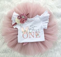 ♥ Some Bunny is One Tutu Set ♥  This sweet Tutu set is sure to be a special addition to your little one's wardrobe. It's perfect for cake smash photos! This tutu is ultra fluffy! Bodysuit has 3 snap closure. The headband is soft and stretchy. Your choice of a flutter sleeve bodysuit or standard.  ORDER TRACKING All orders shipped to the US include tracking. The free shipping option for this item within Canada does not offer tracking. If that is a feature you require please contact me BEFORE orde Cute White First Birthday Sets, Pink Ruffled Birthday Set, Cute White Easter Outfit Set, Cute White Easter Sets, Pink First Birthday Sets For Spring, Pink Sets For First Birthday In Spring, Cute Pink First Birthday Sets, Cute Ruffled Sets For Birthday, Sweet Spring Sets For First Birthday