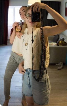 a woman taking a selfie in front of a mirror while holding a camera up to her face