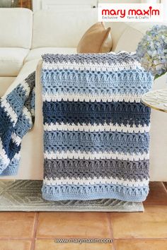 a crocheted blanket sitting on top of a couch next to a white sofa