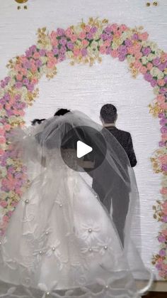 a bride and groom standing in front of a floral wall