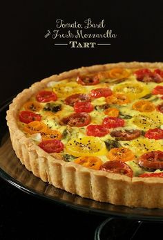 a tomato and cheese tart on a black plate with the words tomato basil & fresh mozzarella tart