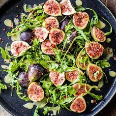 a black plate topped with figs and greens