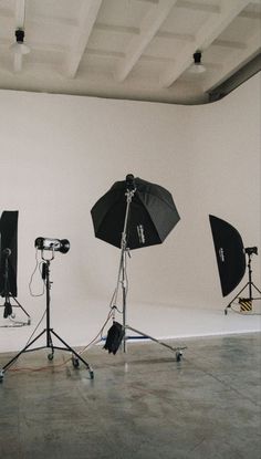 three umbrellas are set up in front of two camera's on the floor