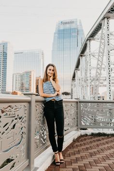 a woman standing on top of a bridge with her arms crossed and looking at the camera