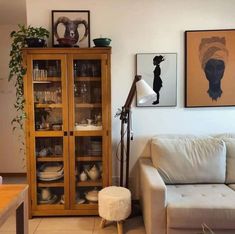 a living room with a white couch and wooden cabinet in the corner next to a coffee table