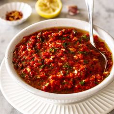 a white bowl filled with tomato sauce and garnished with parsley on the side