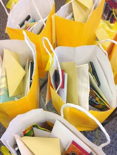 several yellow paper bags filled with notes and pencils