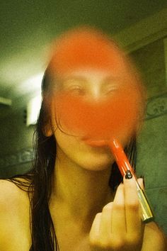 a woman holding a red object up to her face