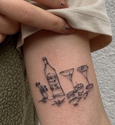 a woman with a tattoo on her arm holding a wine bottle and two cats in the background