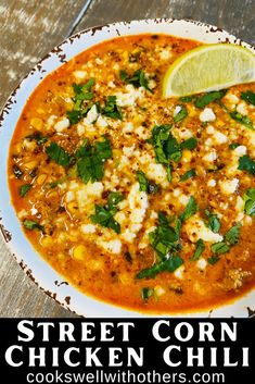 a white plate topped with chicken chili next to a slice of lime and cilantro