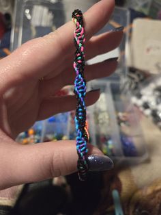 a hand holding a multicolored string bracelet