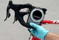 a person wearing gloves holding up a camera to take a photo on a bike with its handlebars