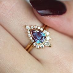 a woman's hand holding a ring with an oval shaped blue and white diamond