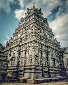 an ornate stone structure in the middle of a park with clouds overhead and blue sky above