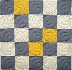 a quilted wall hanging with yellow and grey circles