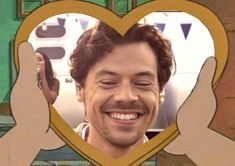 a man smiling and holding his hands up in front of a heart shaped frame