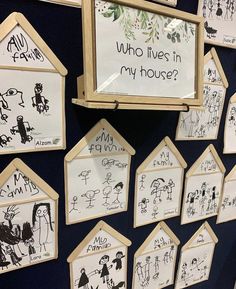 a bunch of drawings are hanging on the wall in front of a sign that says who lives in my house?