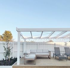 an outdoor living area with white furniture and string lights hanging from the pergolated roof