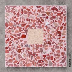 a square shaped tile with red and pink stones on it's side, surrounded by smaller rocks