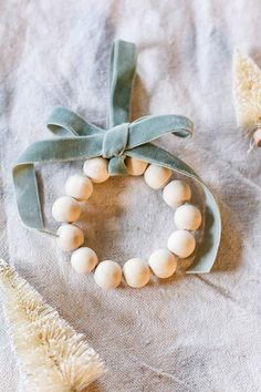 a white beaded bracelet with a green ribbon on top of a piece of cloth