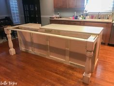 an island in the middle of a kitchen with wooden floors and cabinets on either side