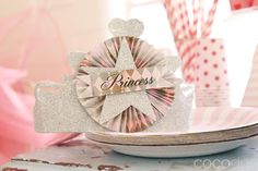 a princess tiara sitting on top of a white plate next to pink and silver paper straws