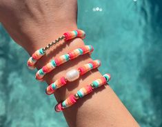 a woman's arm with multicolored bracelets on top of it next to a pool