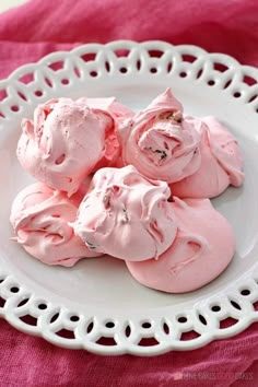 pink meringue cookies on a white plate with a pink towel in the background