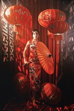 a woman holding an orange umbrella next to red lanterns