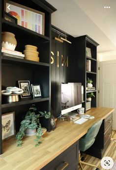 a desk with a computer on top of it next to a book shelf filled with books