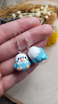 two small blue and white birds sitting on top of each other's ear wires