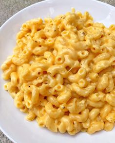 a white plate topped with macaroni and cheese on top of a gray table