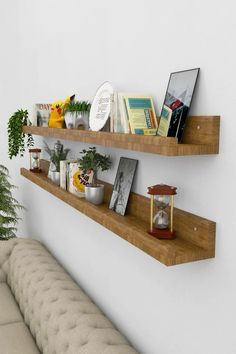 two wooden shelves with books and plants on them next to a couch in a living room