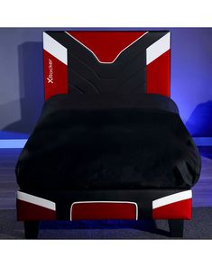 a bed with black, red and white sheets on it's headboard next to a blue wall