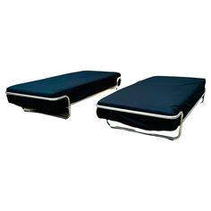 two black beds sitting next to each other on top of a white floor covered in blue sheets