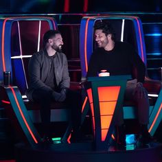 two men sitting in chairs talking to each other on the set of a television show