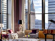 a living room filled with furniture and tall buildings in the background at night, along with a grand piano