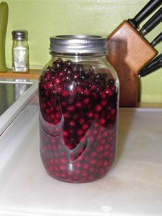 a jar filled with cranberries sitting on top of a counter