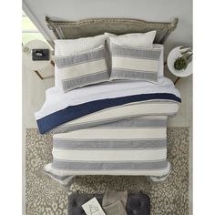 a bed with blue and white striped pillows on top of it next to a nightstand