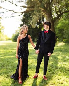 a young man and woman dressed in formal wear holding hands