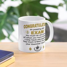 a coffee mug with congratulations written on it sitting on a table next to some books