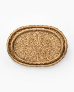 two oval woven placemats on a white background, one is brown and the other is beige