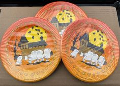 three paper plates decorated with cartoon animals on orange and black background, one is for halloween